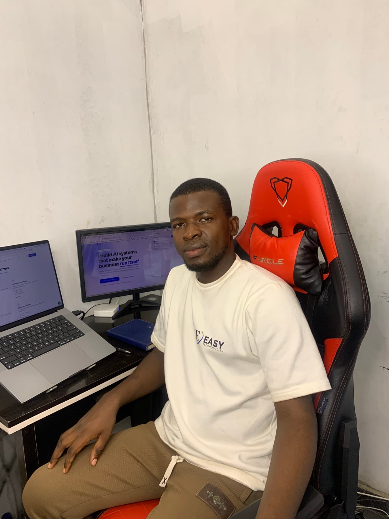 Israel Afolabi at his desk, laptop and monitor showing his portfolio site